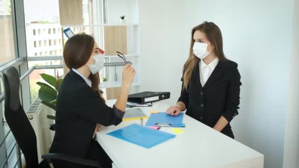 Virksomhedskvinder sidder ved et bord i masker på et kontor med panoramavinduer og forhandler partnerskabsaftaler på det internationale marked. Succes – Stock-video