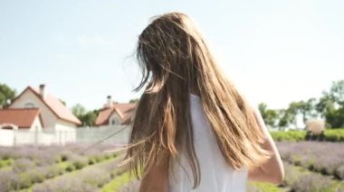 Beyaz elbiseli, güzel bir esmerin portresi. Uzun saçlı ve bir bardak şarapla lavanta tarlasında yürüyen samimi bir gülümseme. Lavanta