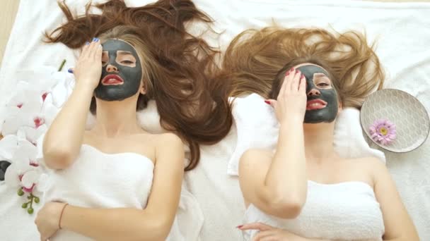여자 아이들은 미용실에서 현대의 온천에서 얼굴을 벗겨 가며 누워 있습니다. 피부의 원기와 건강. 카메라를 위한 모델들. 얼굴에 마스크를 씌우는 모습 — 비디오