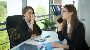 Kadın şirket yöneticileri panoramik pencereli bir ofiste çalışıyorlar. Müşterilerle çalış