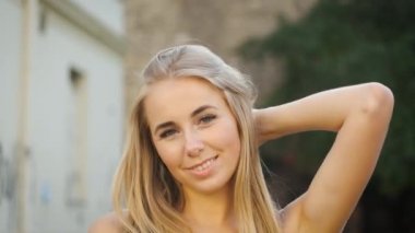 Beyaz görünümlü, samimi bir gülüşü, güzel uzun bir elbisesi ve siyah şapkası olan güzel bir sarışın sabah şehrinde dolaşıyor. Kameranın önünde poz veren bir turist. Model