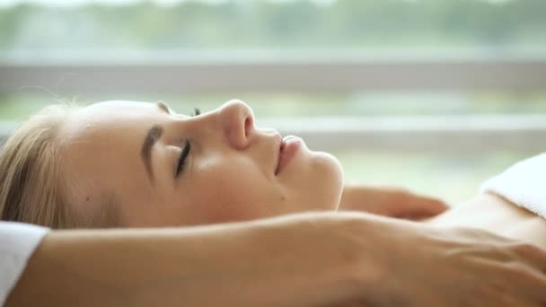 De vrouw heeft een hoofdmassage in een moderne spa met panoramische ramen. Gezondheid en zelfzorg — Stockvideo