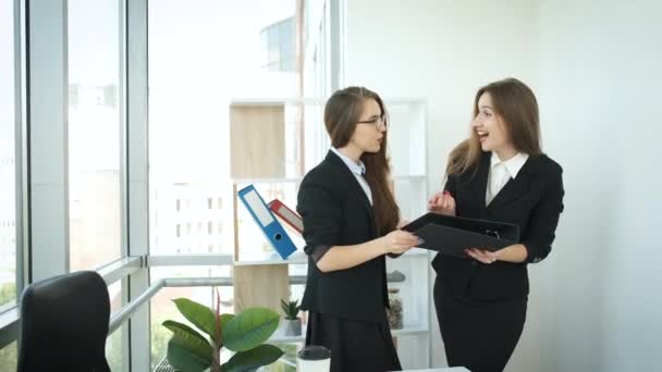 Las mujeres de negocios se sientan en una mesa en una oficina con ventanas panorámicas y acuerdan acuerdos de asociación en el mercado internacional. Éxito — Vídeo de stock