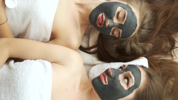 Meisjes liggen in de salon op een gezichtsbehandeling in een moderne spa. Verjonging van de huid en gezondheid. Modellen poseren voor de camera. Aanbrengen van een masker op het gezicht — Stockvideo