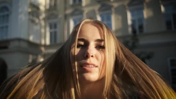 Hermosa apariencia rubia caucásica con una sonrisa sincera y un hermoso vestido largo con un puntal camina por la ciudad de la mañana. Posando frente a la cámara de Turismo. Modelo — Vídeos de Stock