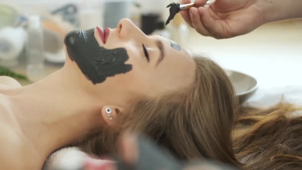 Woman lies on the table in a modern spa and relaxes. Applying a mask to rejuvenate the skin. Health and beauty — Stock Video