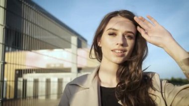 Güzel kız model sokakta durur ve bir şapka takar. Siyah şapkalı, kahverengi pelerinli, uzun saçlı esmer kadın. Arkadan portre çerçevesi