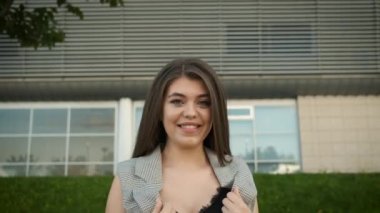 Gri takım elbiseli, beyaz görünümlü güzel bir kız modern ofislerin yanında duruyor.