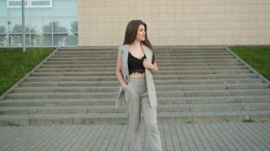 Beyaz görünümlü güzel bir kızın portresi. Ofisin yanında duran gri takım elbiseli, samimi bir gülümsemesi var ve kameraya gülümsüyor. Model