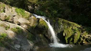 İnanılmaz bir doğa. Dağlarda şelale. Şelaleden akan temiz su ve büyük nehir taşları.