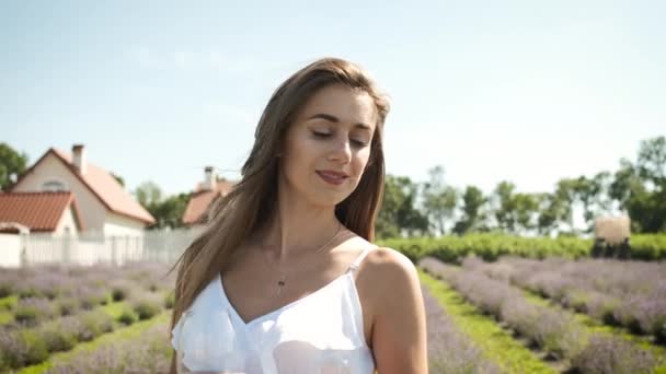 Belle fille brune dans une robe blanche guavaya sur un champ de lavande et boit un verre de vin blanc apprécie les fleurs. Détends-toi. — Video