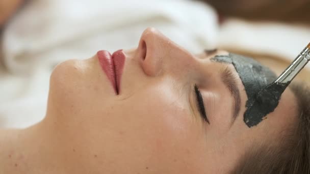 Vrouw ligt op tafel in een modern kuuroord en ontspant. Een masker aanbrengen om de huid te verjongen. Gezondheid en schoonheid — Stockvideo