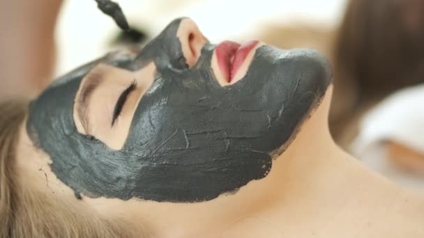 Kvinnan ligger på bordet i ett modernt spa och kopplar av. Applicera en mask för att föryngra huden. Hälsa och skönhet — Stockvideo