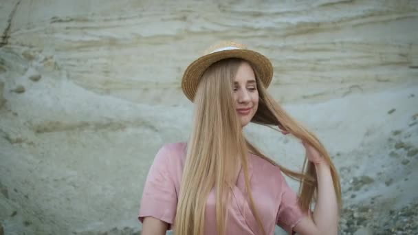 Bella modella bionda in abito rosa e cappello di paglia cammina attraverso il canyon e posa per la fotocamera — Video Stock