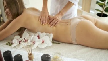 Modern spa merkezindeki güzel sarışın kıza çiçek ve mumlarla masaj masasında. Rehabilitasyon ve sağlık. Rahatla.