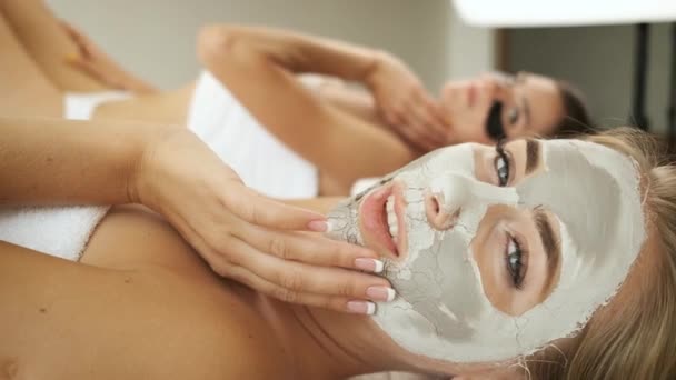 Mooi blond model met een masker op haar gezicht ligt op de tafel in de spa en poseert voor de camera. Huidverjonging — Stockvideo