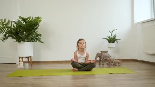 Niña caucásica de 5 años medita en casa. Yoga. Postura de loto. Sanidad — Vídeos de Stock