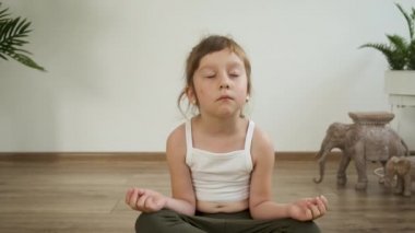 Küçük Kafkasyalı 5 yaşındaki kız evde meditasyon yapıyor. Yoga. Lotus pozu. Sağlık