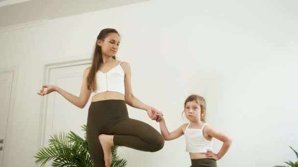 Una madre y su hija de 5 años practican yoga en casa. Meditación y salud — Vídeo de stock