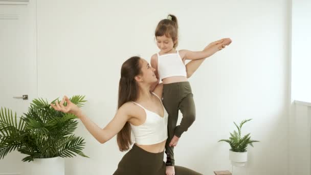 Mutter hält ihre Tochter auf dem Arm und praktiziert zu Hause Yoga. Meditation und Gesundheit. Entspannen — Stockvideo