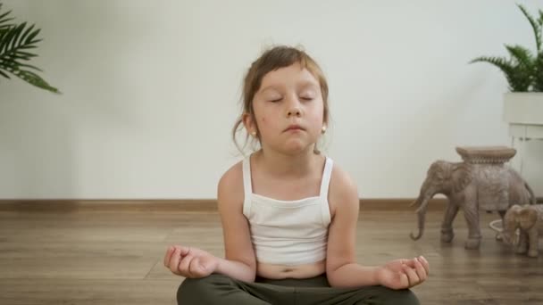 Pequena menina branca de 5 anos medita em casa. Yoga. Posse de lótus. Saúde — Vídeo de Stock