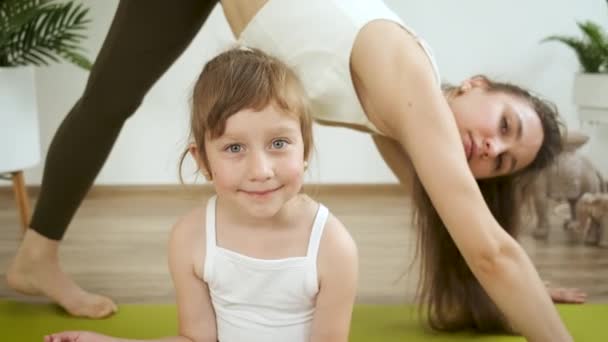 Jovem caucasiana medita com sua filha em casa. Yoga e treinamento de fitness. Alívio ao stress. Saúde — Vídeo de Stock
