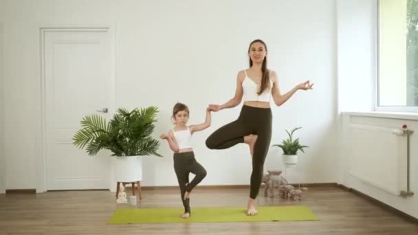 A mother and her 5-year-old daughter practice yoga at home. Meditation and health — Stock Video