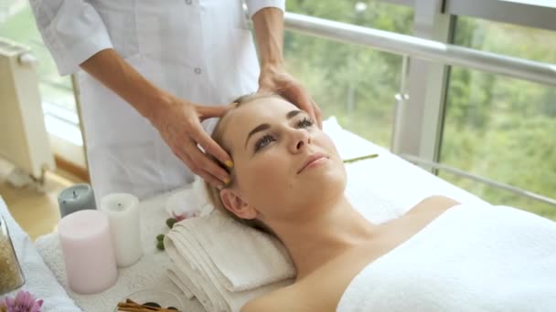 De vrouw heeft een hoofdmassage in een moderne spa met panoramische ramen. Gezondheid en zelfzorg — Stockvideo