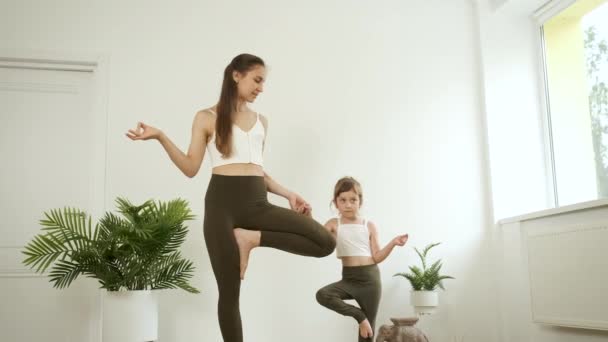 Seorang ibu dan putrinya yang berusia 5 tahun berlatih yoga di rumah. Meditasi dan kesehatan — Stok Video