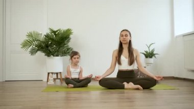 Anne ve kızı yoga yapıyor. Nilüfer pozisyonunda meditasyon yap. Sağlık
