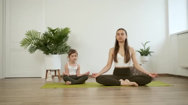 Ibu dan anak berlatih yoga. Bermeditasi dalam posisi teratai. Kesehatan — Stok Video