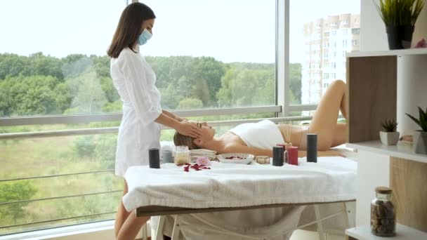 De vrouw heeft een hoofdmassage in een moderne spa met panoramische ramen. Gezondheid en zelfzorg — Stockvideo