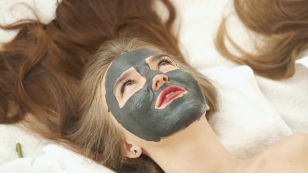 Vrouw ligt op tafel in een modern kuuroord en ontspant. Een masker aanbrengen om de huid te verjongen. Gezondheid en schoonheid — Stockvideo