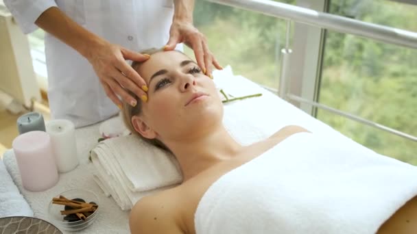 Mujer está teniendo un masaje en la cabeza en un moderno spa con ventanas panorámicas. Salud y autocuidado — Vídeo de stock