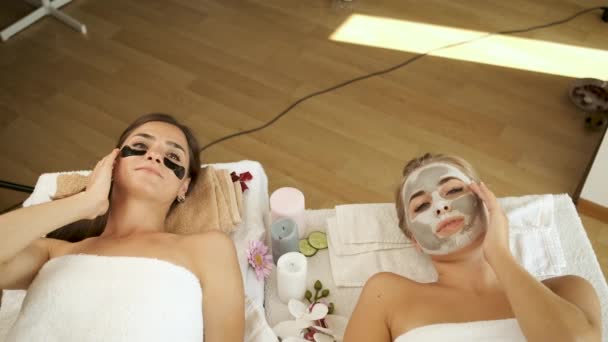 Las niñas se encuentran en el salón en un peeling facial en un spa moderno. Rejuvenecimiento de la piel y salud. Modelos posando para la cámara. Aplicar una máscara en la cara — Vídeo de stock
