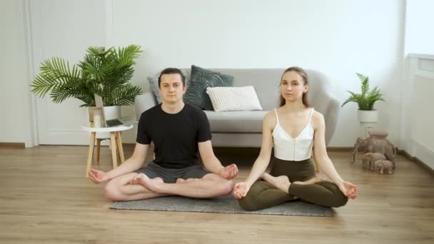 Uomo e donna che fanno yoga a casa. Meditazione. Posizione del loto — Video Stock