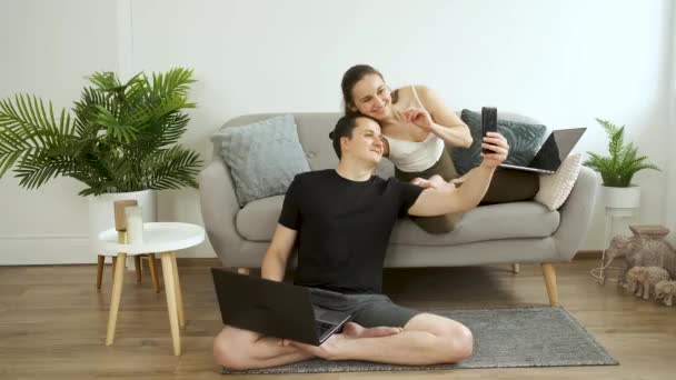 Mann und Frau sitzen allein auf der Couch, halten eine Flasche Wasser in der Hand und telefonieren per Videolink — Stockvideo