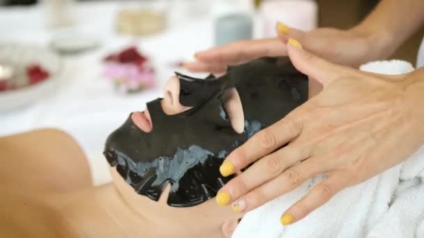 Das Auftragen einer schwarzen Maske auf das Gesicht in einem Wellnessbereich. Hautverjüngung und Gesundheit — Stockvideo