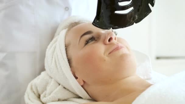 Das Auftragen einer schwarzen Maske auf das Gesicht in einem Wellnessbereich. Hautverjüngung und Gesundheit — Stockvideo