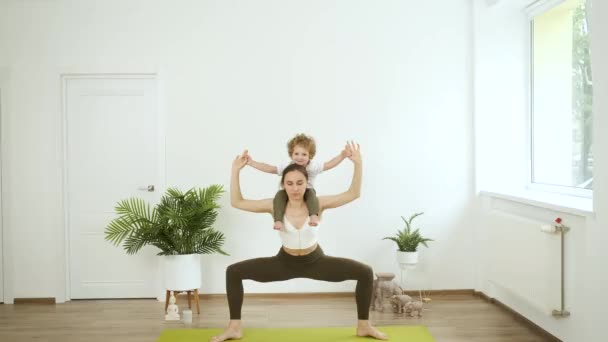 Mamá e hijo pequeño haciendo yoga en casa. Relajación y salud — Vídeos de Stock