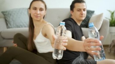 Kadın ve erkek kanepede yerde oturup su içiyorlar. Mutlu bir aile. Sağlık ve diyet