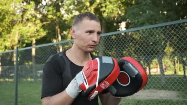 La boxe. Un jeune homme d'apparence caucasienne s'entraîne avec son entraîneur dans la rue. Sports et santé — Video