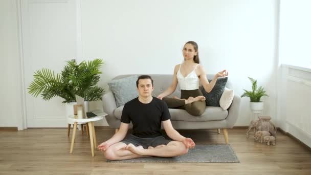 Mann und Frau beim Yoga zu Hause. Meditation. Lotus-Pose — Stockvideo