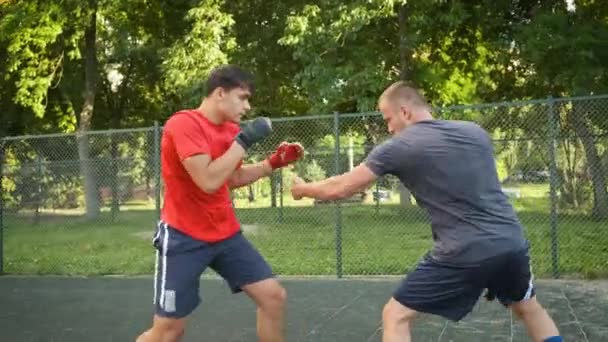 La boxe. Un jeune homme d'apparence caucasienne s'entraîne avec son entraîneur dans la rue. Sports et santé — Video