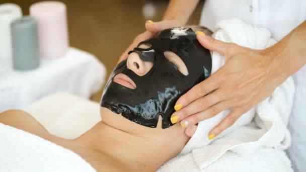 Een zwart masker op het gezicht aanbrengen in een kuuroord. Verjonging en gezondheid van de huid — Stockvideo