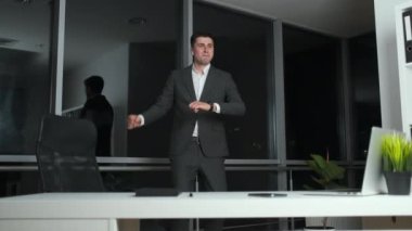Ofisinde panoramik pencerenin yanında dans eden mutlu erkek işadamı. Başarılı bir proje kapatılıyor