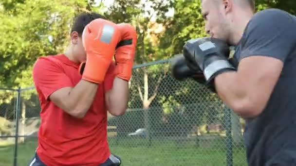 ボクシングだ。白人の青年が通りでコーチと一緒に訓練している。スポーツ・健康 — ストック動画