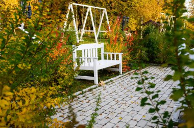 Sarı yaprakların arasında bir sonbahar parkında romantik beyaz bank.
