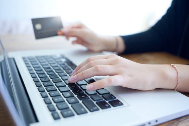kredi kartı tutan ve online alışveriş için dizüstü bilgisayar kullanarak eller