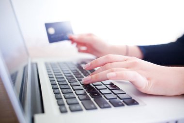 kredi kartı tutan ve online alışveriş için dizüstü bilgisayar kullanarak eller